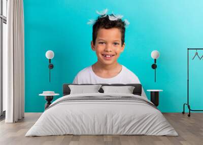 Portrait of cute cheerful kid toothy smile pillow feathers head have good mood isolated on turquoise color background Wall mural