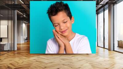 Portrait of cute small boy son wear stylish comfort white pajama two hands touch face cheeks take nap isolated on cyan color background Wall mural