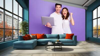 Portrait of ecstatic two people couple work laptop celebrate social network victory raise fists scream yes wear white t-shirt denim jeans isolated over violet purple color background Wall mural