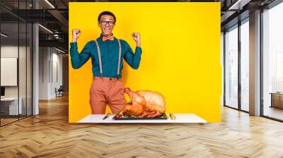 Portrait of elegant young man raise fists roasted thanksgiving day turkey empty space isolated on yellow color background Wall mural