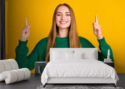 Portrait of girl in green jumper directing fingers up above head proves her experience in cv copyspace isolated on yellow color background Wall mural