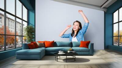 Portrait of happy cute young woman with toothy smile in casual oufit, raised hands, dancing because her dream comes true, standing over grey background Wall mural