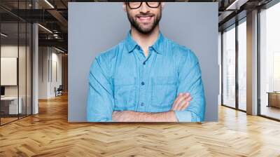 Portrait of happy fashionable handsome man in jeans shirt and glasses crossing hands and smiling Wall mural