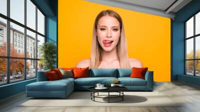 Portrait of happy foolish girl looking camera with tongue out isolated on vivid yellow background Wall mural