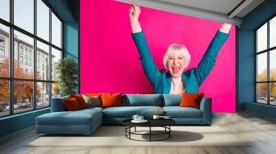 Portrait of her she nice attractive cheerful cheery overjoyed gray-haired lady wearing blue green jacket rejoicing rising hands up isolated on bright vivid shine vibrant pink fuchsia color background Wall mural