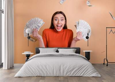 Portrait of her she nice attractive lovely cheerful cheery crazy glad straight-haired girl holding throwing large sum of money budget isolated over beige pastel color background Wall mural