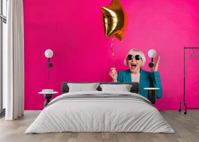 Portrait of her she nice-looking attractive lovely crazy overjoyed cheerful cheery gray-haired lady holding balloon having fun isolated on bright vivid shine vibrant pink fuchsia color background Wall mural