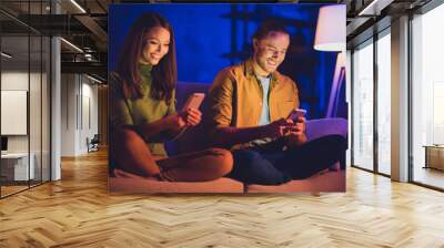 Portrait of his he her she nice attractive lovely cheerful cheery married couple sitting on divan in lotus pose using device gadget 5g app browsing at home house apartment indoors Wall mural