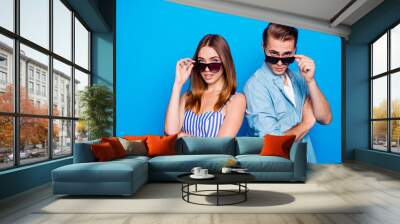 Portrait of his he her she two nice attractive trendy lovely content people partners wearing touching sun specs looking at you isolated on bright vivid shine vibrant blue color background Wall mural