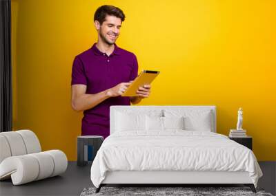 Portrait of his he nice attractive cheerful cheery content guy using digital ebook spending free time isolated over bright vivid shine vibrant yellow color background Wall mural