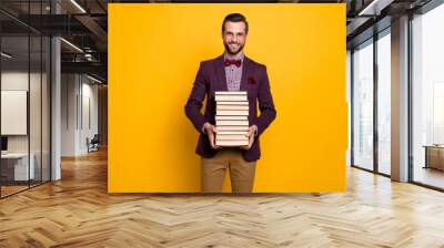 Portrait of his he nice attractive cheerful intelligent guy professor holding in hands many book academic learning isolated over bright vivid shine vibrant yellow color background Wall mural