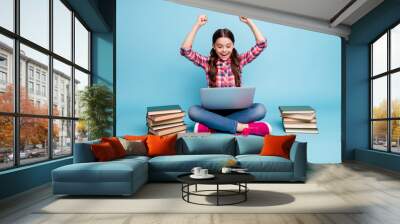 Portrait of nice attractive cheerful cheery positive smart clever girl wearing checked shirt sitting in lotus pose excellent digital web library academic isolated on bright vivid shine blue background Wall mural