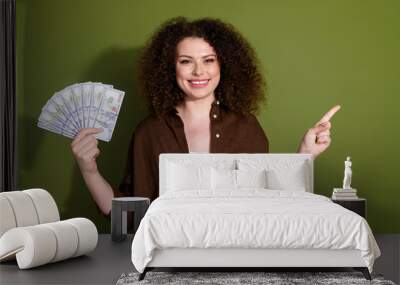 Portrait of nice young girl hold cash point finger empty space wear brown shirt isolated on khaki color background Wall mural