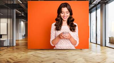 Portrait of positive cheerful girl use smartphone read social media news share information wear knitted outfit isolated over orange color background Wall mural