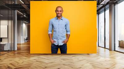 Portrait of pretty guy feel glad hands palms pockets isolated over yellow background Wall mural