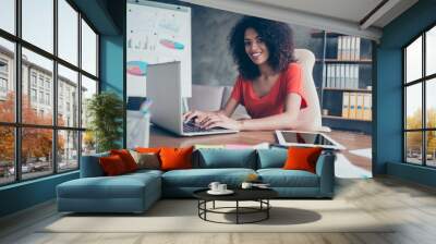 Portrait of representative charming lawyer in casual outfit with beaming smile sitting at desk looking at camera typing on keyboard of laptop using wifi internet Wall mural