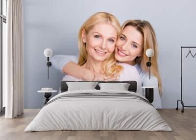 Portrait of stylish cute attractive charming mother and daughter, family with one single parent, warm hugs, looking at camera isolated on grey background Wall mural