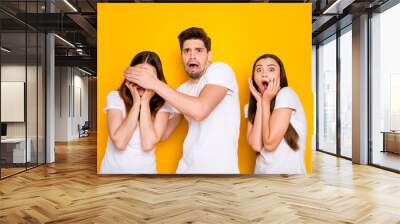 Portrait of three nice attractive lovely nervous devastated frustrated person expressing fear sorrow omg disgust crying isolated over bright vivid shine yellow background Wall mural