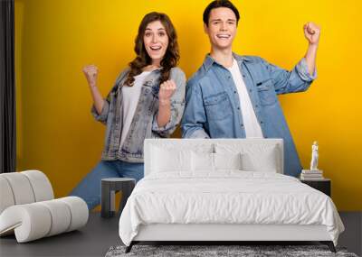 Portrait of two delighted funky people raise fists celebrate achievement isolated on yellow color background Wall mural