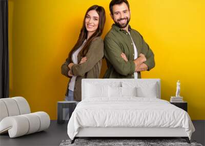 Portrait of two positive friendly partners crossed arms stand back to back isolated on yellow color background Wall mural