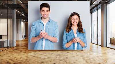 Portrait of two positive students man woman use smartphone feel shy communicate only social network wear good look casual denim jeans shirt isolated over gray color background Wall mural