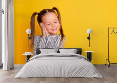 Portrait of young happy smiling girl child kid daydreaming with closed eyes hold hands together isolated on yellow color background Wall mural