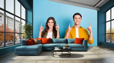 Portrait photo of cheerful good mood smiling couple friendship wear shirts direct fingers mockup university advert isolated on blue color background Wall mural