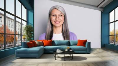 Portrait photo of satisfied smiling senior businesswoman wearing eyeglasses and purple cardigan dreaming planning isolated on grey color background Wall mural