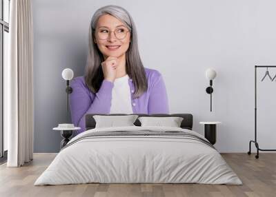 Portrait photo of smart elder intelligent business woman wearing eyeglasses looking at side thinking about idea touching face smiling isolated on grey color background Wall mural