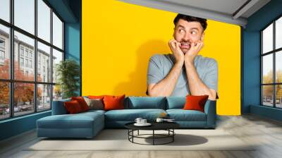 Portrait photo of young funny nervous impressed man shocked biting fingers failed manager mistake look empty space isolated on yellow color background Wall mural