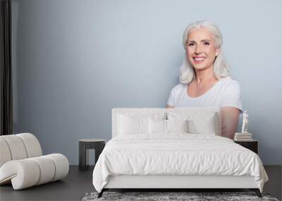 Portrait with copy space of cheerful, happy, aged, mature, nice woman standing with crossed arms over gray background Wall mural