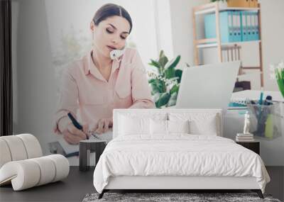 Pretty charming agent talking on telephone with partners colleagues writing down planning time of conference meeting in notebook reminder sitting in modern office with interior Wall mural