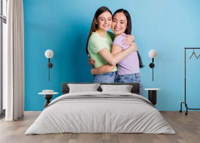 Profile photo of cheerful lesbians couple hugging good mood young students best friends fellows buddies eyes closed wear casual green purple t-shirts jeans isolated blue color background Wall mural