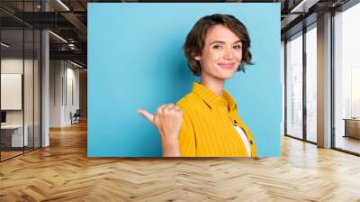 Profile photo of funny millennial brunette lady point empty space wear yellow shirt isolated on blue color background Wall mural