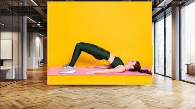 Profile side full body view of nice attractive slender girl trainer lying on mat doing exercise isolated on bright yellow color background Wall mural