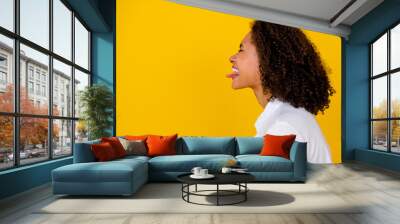 Profile side photo of sweet girl enjoy birthday party celebrate show tongue out eyes closed empty space isolated on yellow color background Wall mural