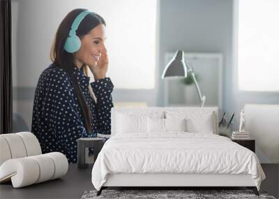 Profile side photo of young attractive beautiful smiling cheerful businesswoman in headphones typing in laptop at office workshop Wall mural