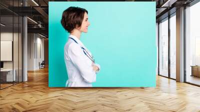 Profile side photo of young woman happy smile folded hands look empty space doctor isolated over teal color background Wall mural