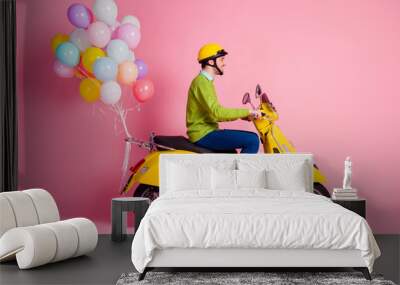 Profile side view of his he nice attractive cheerful cheery glad guy driving moped bringing carrying bunch air balls festive decoration isolated over pink pastel color background Wall mural