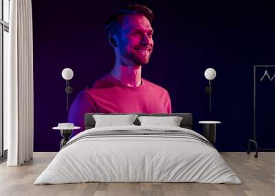 Profile side view portrait of attractive cheerful virile guy isolated over dark neon light violet color background Wall mural