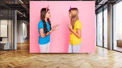 Profile side view portrait of two nice-looking attractive charming cute lovely discontent puzzled confused pre-teen girls arguing isolated on pink pastel background Wall mural