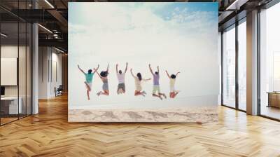 Rear back view photo of positive funny carefree group jump raise arms wear casual outfit nature summer seaside beach Wall mural