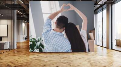 Rear portrait of two young people arms make heart symbol relocating moving box package new apartment indoors Wall mural