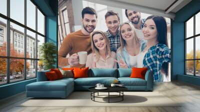 Self portrait of cheerful, joyful, positive students managers shooting selfie on front camera in modern office showing two fingers, like, peace, hi sign, holding cup with coffee, partnership Wall mural