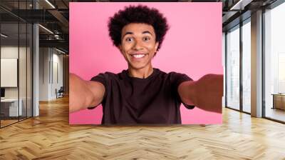 Selfie of young curly hair man in brown t shirt toothy beaming smile guy showing after dentistry clinic isolated on pink color background Wall mural