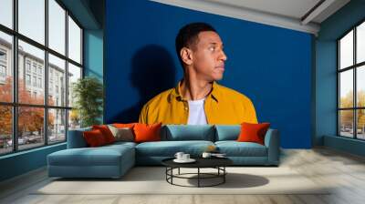 Side profile photo of american young guy wearing stylish shirt with new haircut looking copyspace isolated on dark blue color background Wall mural