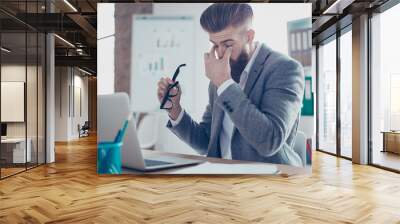 Tired and overworked stylish red bearded manager sitting in front of computer and trying to concentrate, his eyes are dry and hurt Wall mural