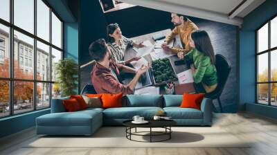 Top above high angle view photo of focused four people investors speak tell talk say start-up development progress report sit desk table in modern workplace Wall mural