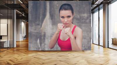 Woman power, self defence concept. Close up portrait of attractive serious fit boxer, ready for fight, on concrete wall background, wearing pink fashionable sport wear Wall mural