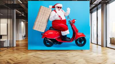 X-mas christmas tradition win full length profile side photo of white grey bearded hair santa claus drive scooter deliver pizza raise fists wear red costume isolated blue color background Wall mural